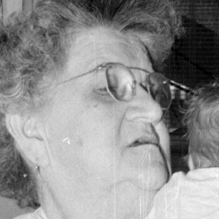 Woman with glasses holding an infant indoors.