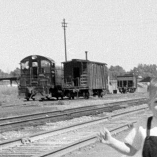 Boy in overalls on a train platform.