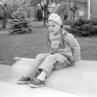 Child in headdress on car hood