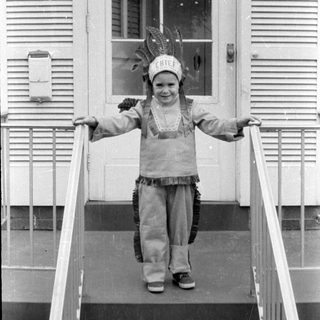 Child in chief costume on porch stairs
