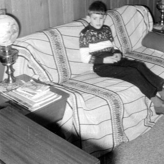 Child on couch indoors, mid-century