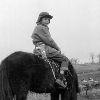 Child riding horse in rural field
