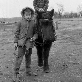 Children riding and leading horse outdoors