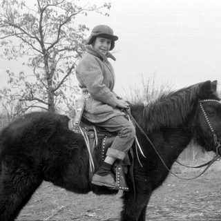 Child riding horse outdoors, rural setting