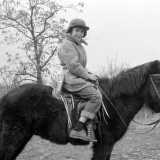 Child riding horse outdoors, rural setting