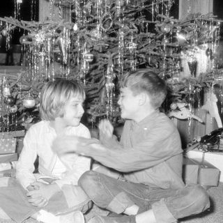 Children by Christmas tree with gifts