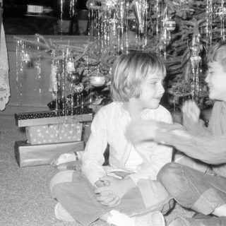 Children by Christmas tree with gifts