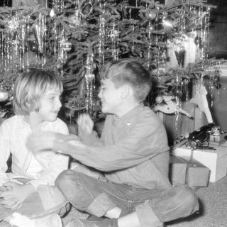 Children by Christmas tree with gifts