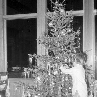 Child decorating a Christmas tree with gifts