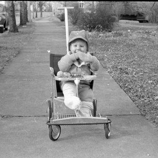 Child in laundry cart on sidewalk