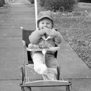 Child in laundry cart on sidewalk