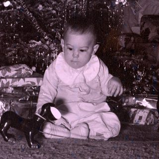 Child with toy dog by Christmas tree