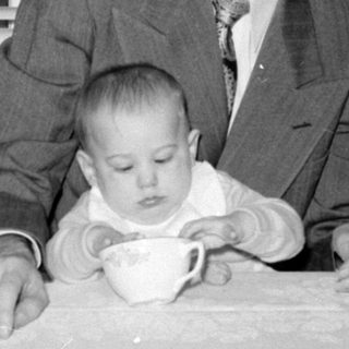 men and baby at tea table