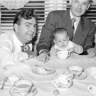 men and baby at tea table