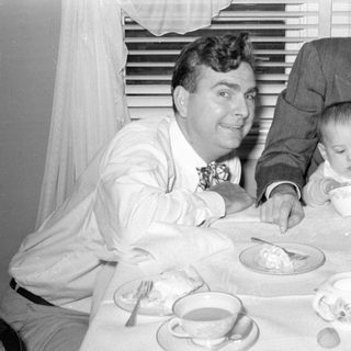 men and baby at tea table