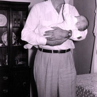 Man cradling baby indoors, mid-century home