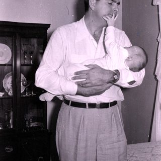 Man cradling baby indoors, mid-century home