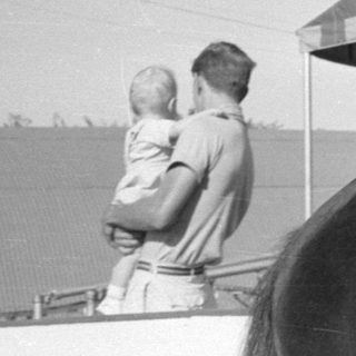 Boy in overalls sitting on a horse.