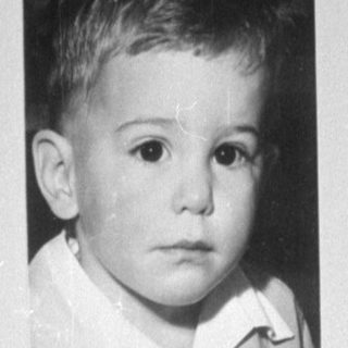 Child sitting next to a framed portrait.