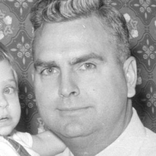 Man and young child against patterned wallpaper.