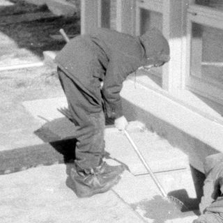 Two people working outside a windowed building.