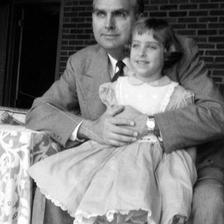 Man in suit and girl in dress outdoors.