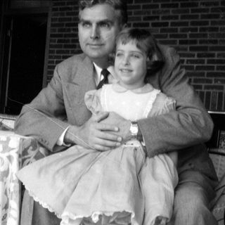 Man in suit and girl in dress outdoors.