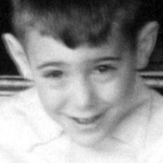 Boy holding a magazine in front of a fireplace.