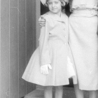 Woman and two children in formal attire on porch.