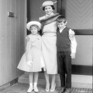 Woman and two children in formal attire on porch.