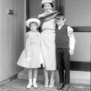 Woman and two children in formal attire on porch.