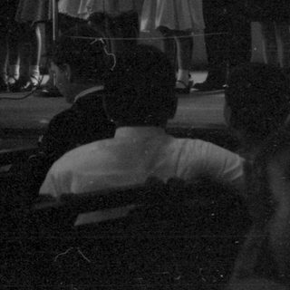 Children performing on a stage in a hall.