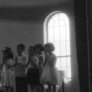 Children performing on a stage in a hall.