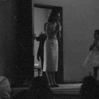 Children performing on a stage in a hall.