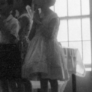 Children performing on a stage in a hall.