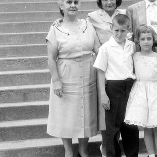 Family group portrait on stone steps, mid-century style.