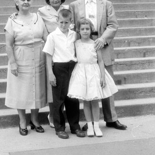 Family group portrait on stone steps, mid-century style.