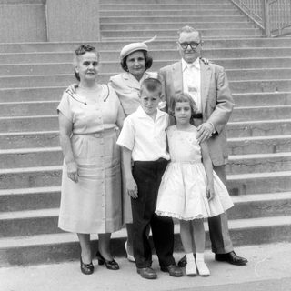 Family group portrait on stone steps, mid-century style.