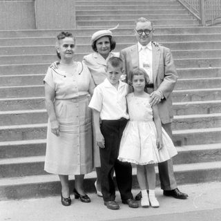 Family group portrait on stone steps, mid-century style.