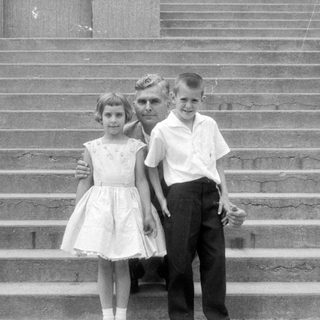 Man and three children on concrete stairs.
