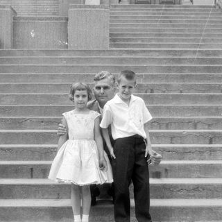 Man and three children on concrete stairs.