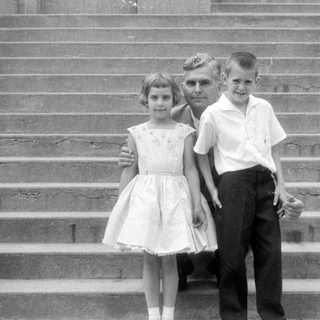 Man and three children on concrete stairs.
