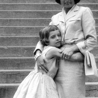 Woman and young girl standing on stone stairs.