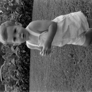 Young child in a romper outdoors.