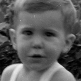 Young child in a romper outdoors.