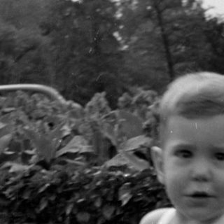 Young child in a romper outdoors.