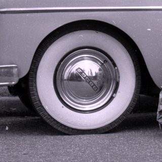 Woman and child posing beside a vintage sedan.