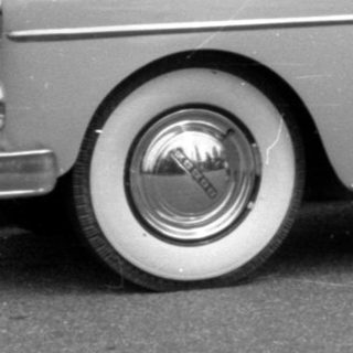 Woman and child posing beside a vintage sedan.