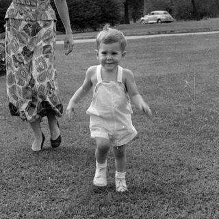 Woman and child walking on a grass lawn.