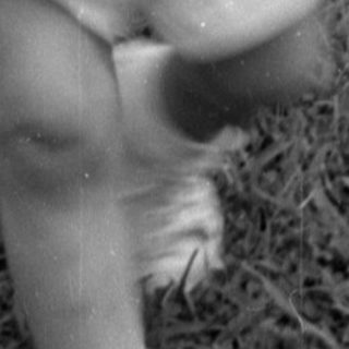 Young child in overalls walking on a lawn.